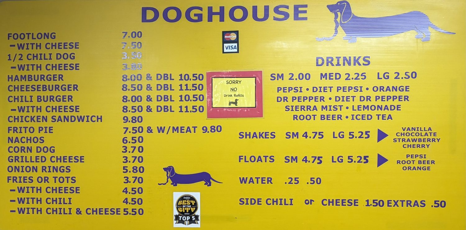 A bright yellow menu board lettered in purple, headed DOGHOUSE, with a purple dachshund illustration, a Best of the City 2023 Top 5 badge, and a red-bordered sign reading SORRY NO Drink Refills.
